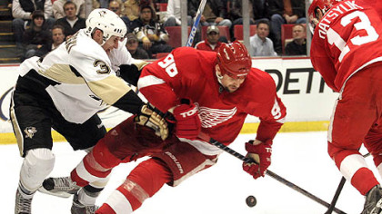 Red Wings forwards Tomas Holmstrom and Pavel Datsyuk battle for the puck with Penguins defenseman Alex Goligoski during the second period.