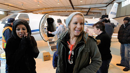 Jamie, left, and Ali McMutrie wait in the chill of an open Corporate Air hangar at Allegheny County Airport as the plane that will take them to Haiti is loaded with supplies for their BRESMA orphanage.