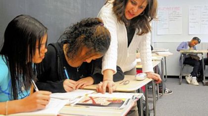 Danielle Harris, a reading coach at Pittsburgh Classical Academy, helps students Brooklynne Smith, left, and Elissa Edmunds with work in Mike Nolf's eighth-grade communications class.