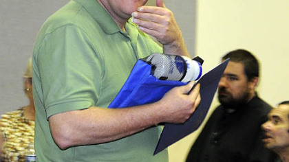 John Edward signs "thank you" at the awards ceremony for the 23rd annual Flowering of Insight art exhibit.