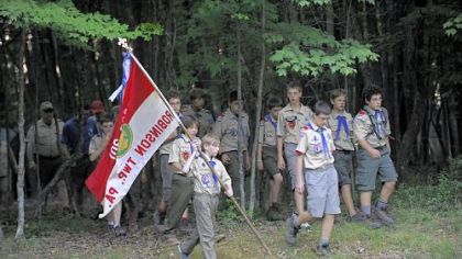 Drake Palmer, 12, of Troop 301 in Robinson, carries the flag to the flag-lowering ceremony at Camp Liberty.