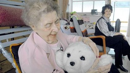 Millie Lesek, 89, pats Paro, a $6,000 furry robot at Vincentian Home in McCandless. At right is Eileen Oldaker, her daughter.