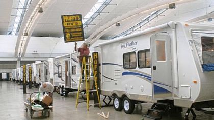 Workers help put up signs marking the trailers displayed by Huffy's RV & Trailer Sales, of Finleyville, at the Pittsburgh RV show at the David L. Lawrence Convention Center.
