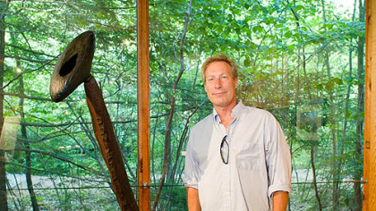 Bill Zarvis stands next to his glass and wood scuplture.