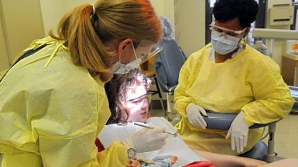 Allyson Feinstein, pediatrics dental resident, examines 12-year-old patient Samantha Agostino of Cuddy at the Pitt dental clinic with Debra Evans, dental assistant, standing by.