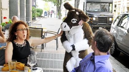 Judi McNeil of Ross admires Lindsay Hoer, 12, of Yonkers, N.Y., who is attending the Anthrocon convention Downtown this weekend dressed as a doe. Also dining along Penn Avenue on Friday is Ron Green, right, of Wilkinsburg.