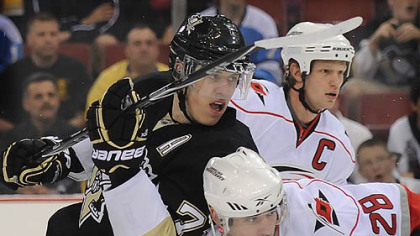 Penguins forward Evgeni Malkin battles for position with Hurricanes defenseman Jamie McBain. Carolina captain Eric Staal is in the rear.