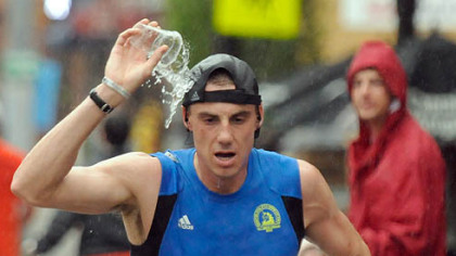 Despite running in a pouring rain, Chris Rotelli pours his cup of water over his head as he runs along East Carson Street.