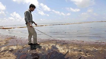 Louisiana Gov. Bobby Jindal walks through oil that got past booms as he tours a land bridge built by the Louisiana National Guard on Friday in Grand Isle, La.