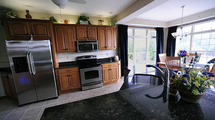 The open kitchen boasts oak cabinetry, granite-topped counters, brick-sided peninsula with bar sink, ceramic-tile floors and stainless-steel GE appliances less than a year old.