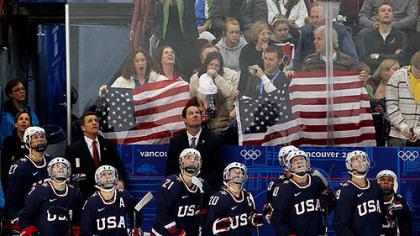U.S. coach Mark Johnson and his players look up at Canada Hockey Place's giant video scoreboard during the victory Monday against Sweden.