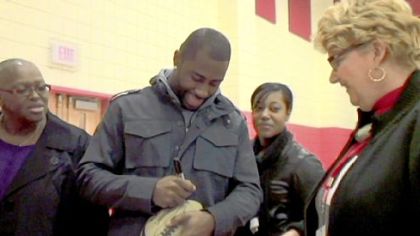 Aliquippa native Darrelle Revis of the New York Jets signs a football at Aliquippa Elementary School on Monday.