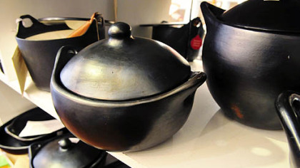Various types of black clay cooking vessels sit on shelves inside the Annex Cookery store in Homestead.