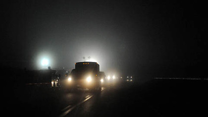 Vehicles pass giant flood lights illuminating an entrance to Massey Energy Upper Big Branch mine in Raleigh County after an explosion there killed at least 25 people, Monday.