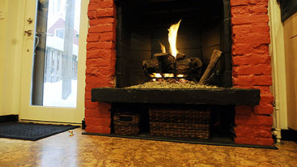 A gas fireplace with a bright-red brick hearth casts a warm glow on the Rushing's kitchen cork floors. A glass back door offers a view of the deck and yard.