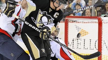 Sidney Crosby tries to knock the puck out of the air against Capitals goalie Jose Theodore in the first period.