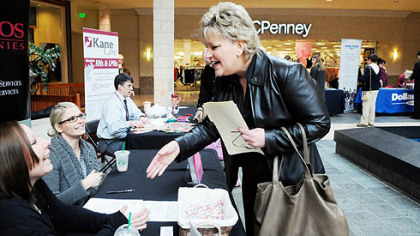 Suzanne Chichester greets representatives of the Callos Companies as she interviews at the tables set up by firms seeking workers at a job fair in Robinson.