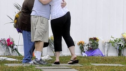People gather Wednesday night at a memorial display at the LA Fitness Center in Collier.