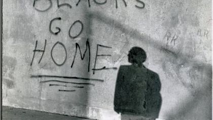 A bystander reads graffiti on the wall of a school in Glendale, N.Y., on Sept. 14, 1959, after black students were transferred from schools in the Bedford-Stuyvesant area of Brooklyn to the predominantly white Queens school.