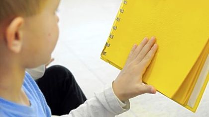 Kindergarten student Adam Janesko experiences the dots in a sample braille book.