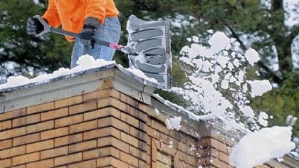 Alan Barrett shovels snow from the flat roof of a two-story building at 600 Nobelstown Road in Pittsburgh's West End Thursday afternoon.