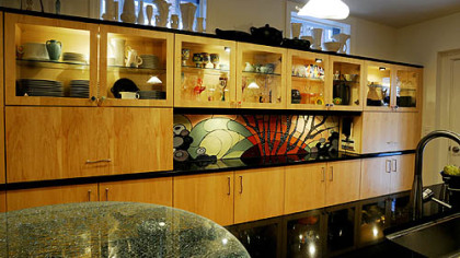 A wall of custom maple cabinets offer pretty display of Darlene Rushing's collection of McCoy and Tierra Negra pottery and art glass. The cracked glass table top at the end of the island (foreground) came from Art Glass Sales in the South Side.