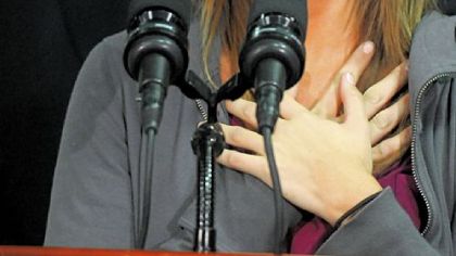 Ali McMutrie  brings her hands to her chest as she talks about seeing her parents in Haiti, with Gov. Ed Rendell behind her during news conference at Atlantic Aviation at the airport.