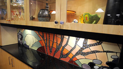 Shari Lynn Bennett of Magnificent Manufacturing in Allegheny West designed the custom tile backsplash in Darlene and Derwin Rushing's Mexican War Streets kitchen. It depicts tree branches and wooly Truffalo trees. The glass cabinets above display the couple's extensive collection of ceramics and art glass.