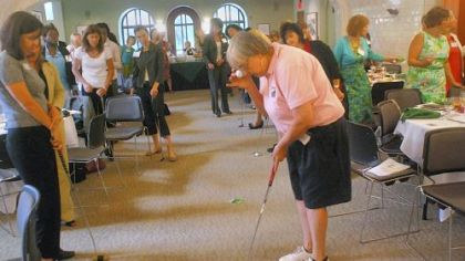 Sandy Thomas demonstrates a trick about putting stance for a women's entrepreneurship luncheon Tuesday at Chatham University: Hold a ball to your eye, let it drop, and if you are in the correct stance over the ball, the falling ball will hit the one on the ground.
