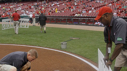 Members of the Reds' grounds crew paint a sign in the dirt behind home plate directing fans to an Internet site where they can vote for Reds players to the National League All-Star team.