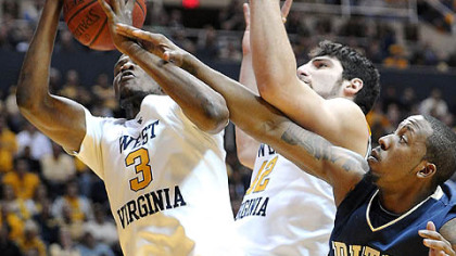 J.J. Richardson tries to get a hand in on a rebound pulled down by West Virginia's Devin Ebanks (3) in the first half Wednesday night in Morgantown, W.Va.
