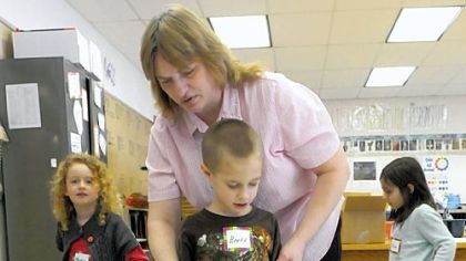 His eyes closed tight, kindergarten student Brett Smith uses a mobility cane as he is helped by class assistant Gloria Maben, making his way among classmates trying out crutches and walkers.