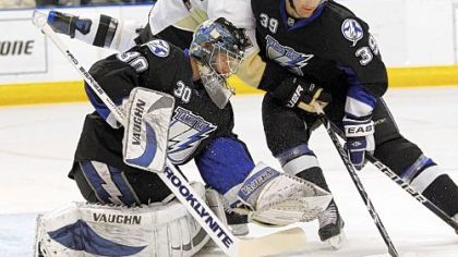 The Penguins' Chris Kunitz, center, has the puck tipped up near his head while battling Tampa Bay Lightning goalie Antero Niittymaki and Mike Lundin.