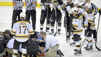 Referees and players watch as Marc Savard is attended to after taking a hit to the head by Matt Cooke.