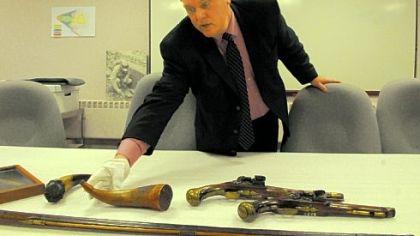 Fort Pitt Museum Director Alan Gutchess works with the display of powder horns and pistols as  the museum prepares to reopen Saturday.