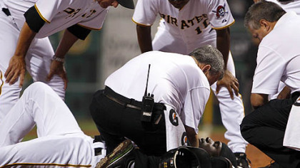 The Pirates' Andrew McCutchen is cared for by trainers Brad Henderson, bottom center, and Mike Sandoval, right, with manager John Russell, left, coach Tony Beasley, top center, during the second inning.