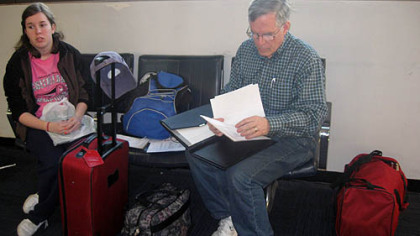 In Newark Airport, New Jersey, travel editor Bill Reed, right, sorts through itineraries between phone calls to Expedia to work out a canceled leg of the return flight. His daughter Rebecca looks on at left.