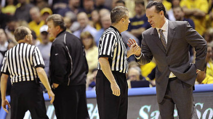 West Virginia head coach Bob Huggins, left, and Pitt coach Jamie Dixon talk with officials after a tussle between players occurred in the second half of Wednesday's game in Morgantown W.Va. Fans threw debris on the court twice during the contest.