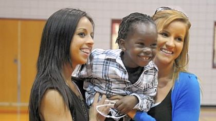 Jamie McMutrie, left, and her sister Ali McMutrie hold their new brother, Fredo, 4, of Haiti, after ceremonies announcing a new scholarship in their honor were held at Avonworth High School.