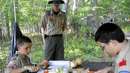 Martin Raitt, left, 10, and Joey Calabro, 14, right, chop carrots for dinner as Eric Hochendoner,  center, 15, looks on.
