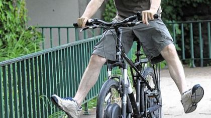 Joe Balena rides a battery-powered bicycle on the South Side. The bike has a battery pack on the front wheel and a motor on the rear wheel.
