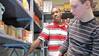 Cedric Saunders, left, and Brian McLain help stock the food pantry shelves at the church.