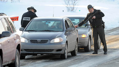 Two Pennsylvania State Police troopers search cars coming from Bredinsburg Road as part of a manhunt for the man who killed a fellow state trooper.