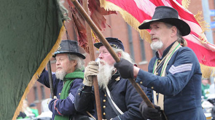 L to R: William Williams of Hempfield, Johnnie Emmons of West Virginia, and Bob Lucas of Erie carry Irish and U.S. flags as they lead the 116th Pennsylvania Company I re-enactors down the Boulevard of the Allies in Downtown Pittsburgh during the St. Patrick's Day parade today.