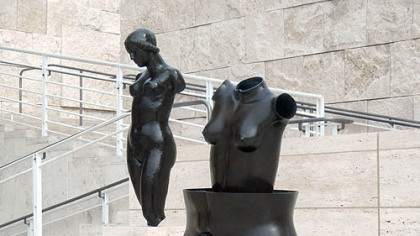 Sculptures are displayed outside and inside the Getty Center's galleries in Los Angeles, California. In this courtyard, the headless Delusions of Grandeur, a 1967 bronze by Rene Magritte, stands next to Torso of Dina, a 1943 bronze by Aristide Maillol.