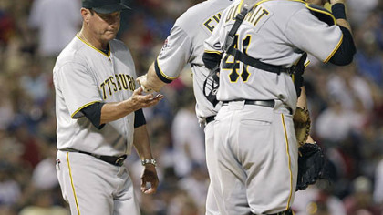 Pirates manager John Russell, left, pulls relief pitcher Dana Eveland as catcher Ryan Doumit adjusts his helmet during the fourth inning.