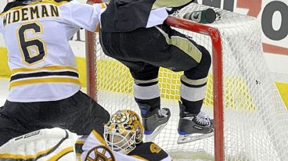 Penguins' Chris Kunitz flies into the upper crossbar over Bruins goaltender Tim Thomas.