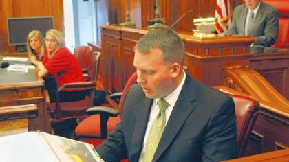 David Brown, of Duquesne University, playing the part of a farmhand whose limbs were damaged in a hay baler accident, looks at evidence photos of the baler as part of his mock case.