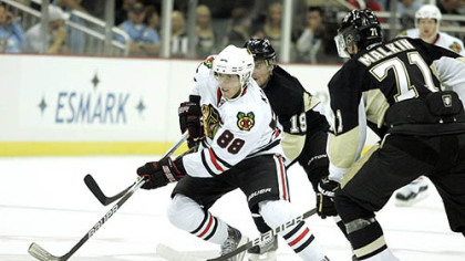 Blackhawks forward Patrick Kane handles the puck against Penguins forwards Evgeni Malkin Mike Comrie.