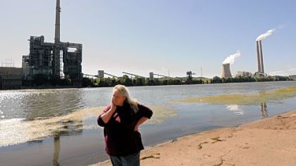 Elisa Young stands along the banks of the Ohio River in Meigs County, Ohio, with the Philip Sporn and Mountaineer power plants on the West Virginia side of the river. There are two other power plants on the Ohio side of the river.